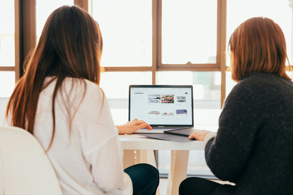 Two women sitting at a table shopping online